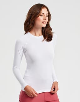 A white long-sleeve underscrub baselayer worn by a woman, featuring a fitted design and a simple style.