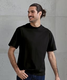 An oversized black T-shirt displayed on a smiling man, featuring a simple design and short sleeves.