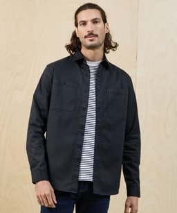 A black button-up shirt with a collar and two chest pockets, worn over a striped t-shirt. It features a logo.