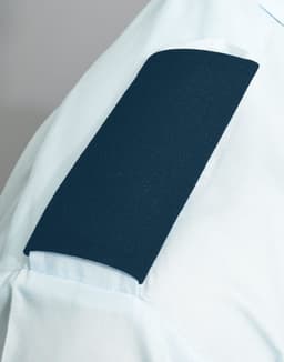 A blue epaulette on a light blue shirt sleeve, featuring a smooth, textured surface. The image includes branding.