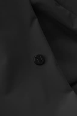 A black jacket featuring a textured surface and a round logo badge on the front.
