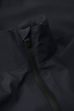 A navy men’s jacket featuring a high collar and zip closure. The fabric is smooth and appears water-resistant.