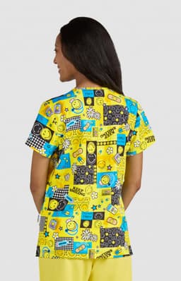 A vibrant yellow top featuring a playful print with various patterns, smiley faces, and graphic elements.