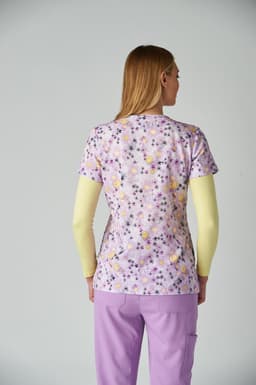 A floral-patterned purple top with short sleeves, worn over a long-sleeved yellow top, with matching purple trousers.