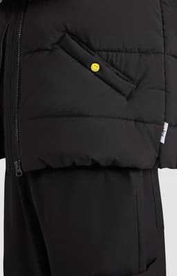 A black puffer vest with a side pocket and a yellow button detail, featuring a zip closure on one side.