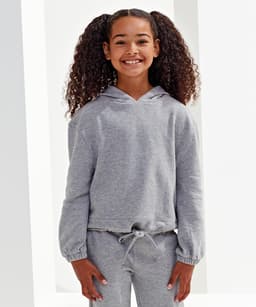 A grey, cropped oversize hoodie displayed on a smiling girl with curly hair, featuring a drawstring at the waist and a logo.