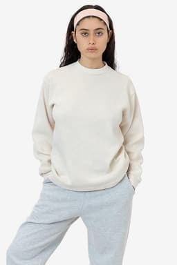 A model wearing a cream-coloured heavy thermal crewneck jumper with long sleeves, paired with grey pants.