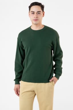 A man wearing a dark green heavy thermal crewneck jumper paired with beige trousers, featuring long sleeves.