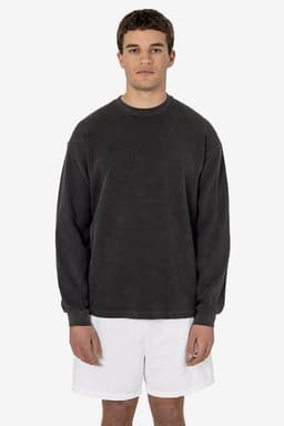 A man wearing a dark grey heavy thermal crewneck jumper and white shorts, standing against a plain background.