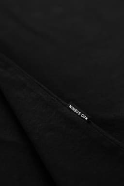 A black T-shirt displaying a tag featuring a logo. The fabric appears soft and fold is visible.