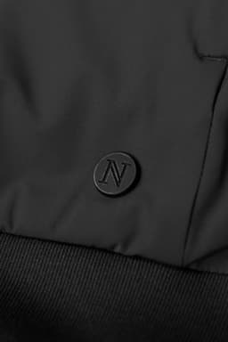 A black hybrid jacket featuring a textured fabric and a small branding logo on the surface.