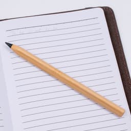A bamboo pen resting on a lined notebook page, featuring a simple and natural design.