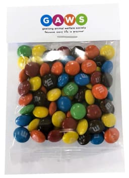 A clear bag filled with colourful M&M chocolates, featuring a mix of red, yellow, blue, green, and brown sweets.