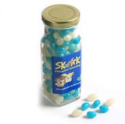 A tall glass jar filled with blue and white mini jelly beans, with a gold lid and a logo on the front.