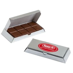 A silver box contains a milk chocolate bar with several segments inside. The box features a logo.