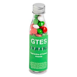 A drink bottle filled with green, red, and white chewy fruit candies. The bottle features branding on its label.