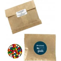 A kraft paper bag containing chewy fruit candies in vibrant colours, alongside a branded circular logo.