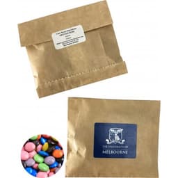 A Kraft paper bag containing colourful choc beans, with a logo on the front. The bag is brown and sealed at the top.