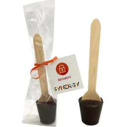 A chocolate spoon in a clear packet with an orange ribbon and a wooden stick, featuring a branded tag.