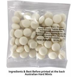 A clear bag containing white mints with visible round discs. The bag has a branding logo and ingredient details on the back.