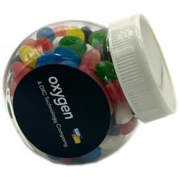 A clear plastic jar filled with colourful jelly beans, featuring a white lid and a logo on the front.