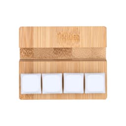 A bamboo stand featuring three white square stress reliever blocks on a smooth surface.