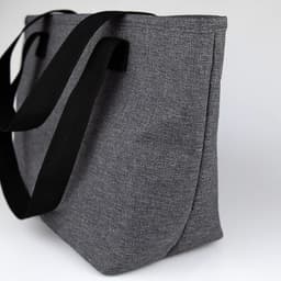 A grey lunch bag with black straps, featuring a simple design and an external logo.
