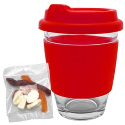A reusable coffee cup with a red silicone sleeve and lid, accompanied by a pack of colourful jelly sweets.