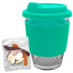 A reusable coffee cup with a turquoise silicone sleeve and a transparent glass body, accompanied by a pack of jelly candies.