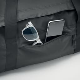A black duffle bag with a mobile phone and sunglasses visible in its pocket. The bag features a logo.