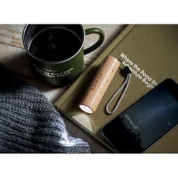A drink bottle in wood and metal beside a coffee cup, notebook, phone, and knitted sweater on a wooden table.