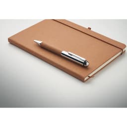 A brown notebook with a pen resting on top, featuring a simple design and a logo on the cover.
