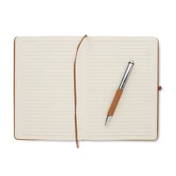 A brown notebook with lined pages and a silver pen resting on it. The notebook features a ribbon bookmark.