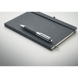 A black notebook and a sleek black pen are arranged on a light surface. The notebook has a logo on the cover.