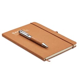 A tan notebook with a rubber band closure and a silver pen resting on top, featuring a logo on the cover.