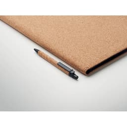 A cork notebook and a black pen on a light background, showcasing natural cork texture.