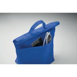 A blue tote bag with a front pocket holding a smartphone and sunglasses. The bag features a top handle.