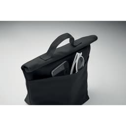 A black tote bag with a handle and a pocket containing a smartphone and sunglasses. It has a simple, modern design.