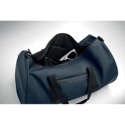 A navy blue duffle bag with black handles, featuring an interior pocket holding a pair of sunglasses.