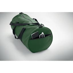 A green duffel bag with black straps, featuring a zippered pocket and a smartphone inside.