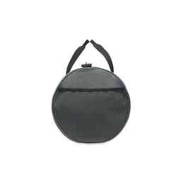 A round, grey bag with a textured surface and a black strap for easy carrying. It features a zippered top and netted panel.