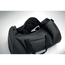 A black duffel bag with an open top, revealing interior compartments and a pair of sunglasses inside.