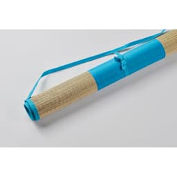 A rolled mat with a natural straw texture and a vibrant blue fabric strap and handle. Features a logo.