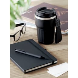 A drink bottle in black with a silver band, alongside a notebook, pen, glasses, and some business cards on a wooden surface.