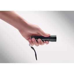 A black flashlight held in a hand, featuring a keyring attachment for easy carrying.