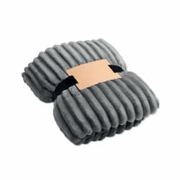 A soft grey throw blanket neatly folded and secured with a black strap and a cardboard label.