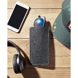 A grey felt glasses case rests on a wooden surface, alongside headphones, a cap, and a smartphone.