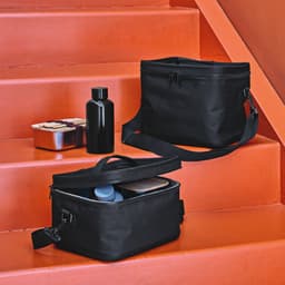 A black cooler bag and a black drink bottle on orange steps, with a metal container beside them.