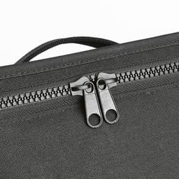 A grey cooler bag featuring thermo-injected zippers and a textured surface. Branding is visible on the exterior.