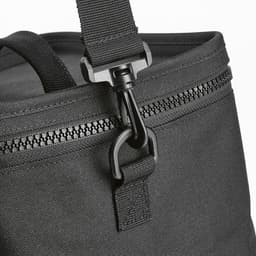 A black cooler bag with a thermo-injected zipper and adjustable strap. It features a durable design suitable for outdoor use.